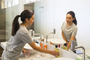 Persona en el lavabo del baño que busca enjuague para verterlo en una taza vacía.